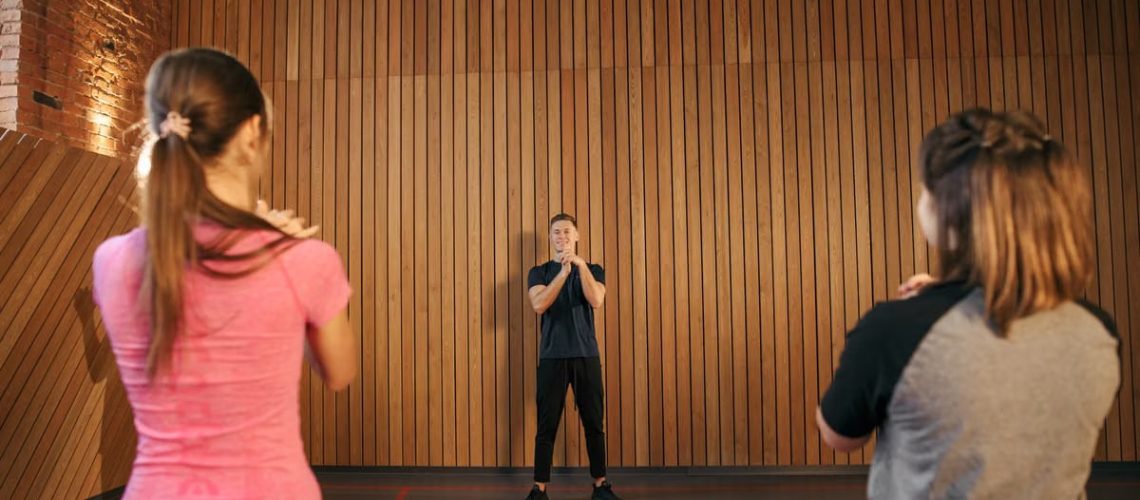 Fitness instructor leading a training session with two women in a modern gym setting.